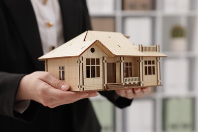 Photo of Real estate agent holding house model in office, closeup