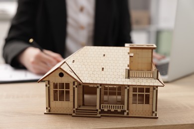 Photo of Real estate agent working at desk in office, focus on house model