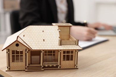 Photo of Real estate agent working at desk in office, focus on house model