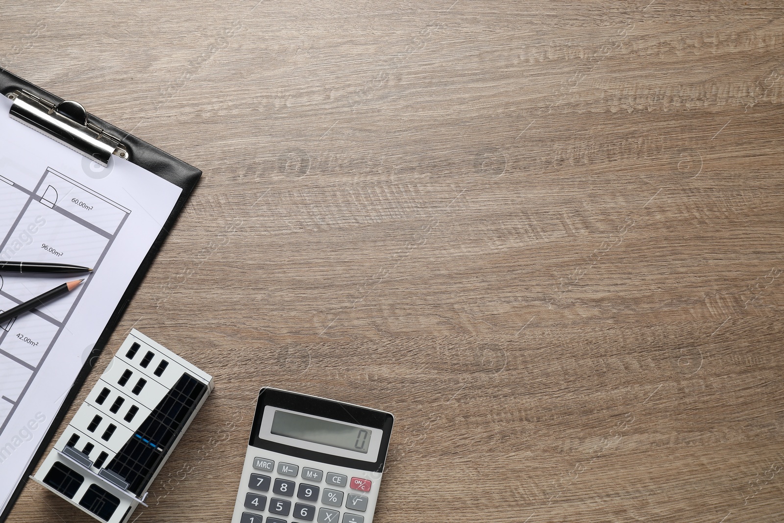 Photo of Real estate. Apartment building model, floor plan and calculator on wooden table, flat lay. Space for text
