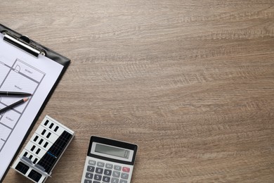Photo of Real estate. Apartment building model, floor plan and calculator on wooden table, flat lay. Space for text