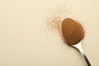 Photo of Spoon with instant coffee on beige background, top view. Space for text