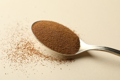 Photo of Spoon with instant coffee on beige background, closeup