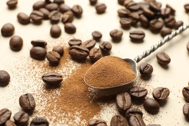 Photo of Spoon with instant coffee and beans on beige background, closeup