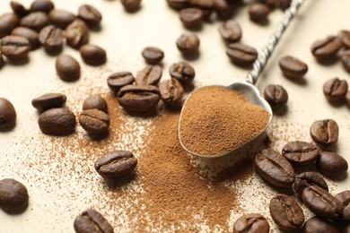 Photo of Spoon with instant coffee and beans on beige background, closeup