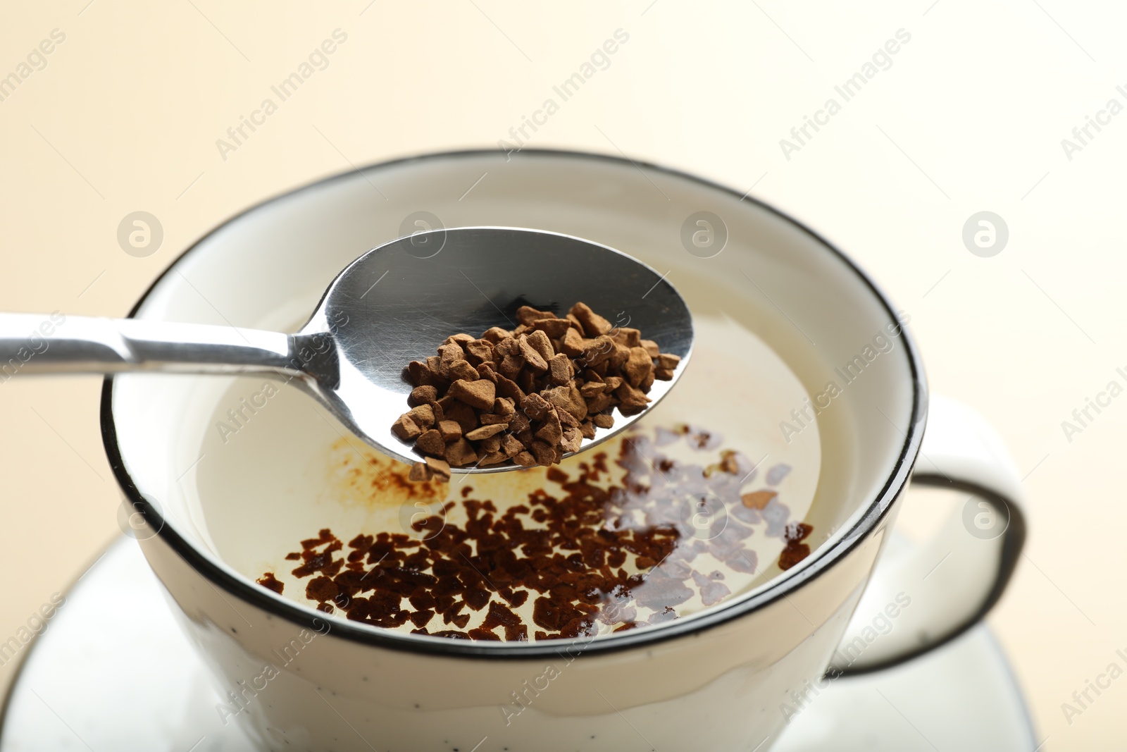 Putting instant coffee into cup on beige background, closeup Photo of Putting instant coffee into cup on beige background, closeup