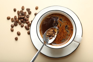Photo of Putting instant coffee into cup on beige background, top view
