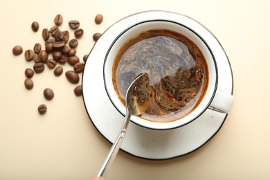 Photo of Putting instant coffee into cup on beige background, top view