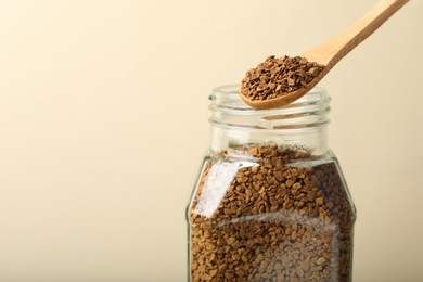 Photo of Taking instant coffee with spoon on beige background, closeup. Space for text