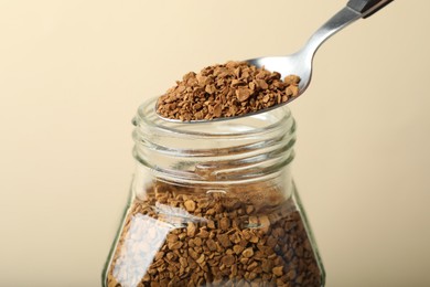 Photo of Taking instant coffee with spoon on beige background, closeup