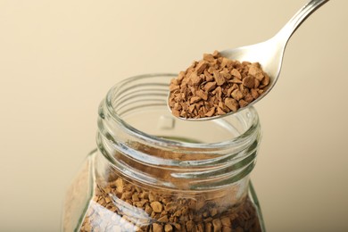 Photo of Taking instant coffee with spoon on beige background, closeup