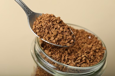 Photo of Taking instant coffee with spoon on beige background, closeup