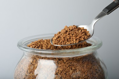 Photo of Taking instant coffee with spoon on grey background, closeup
