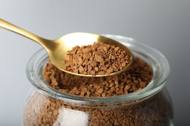 Photo of Taking instant coffee with spoon on grey background, closeup