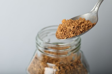 Photo of Taking instant coffee with spoon on grey background, closeup