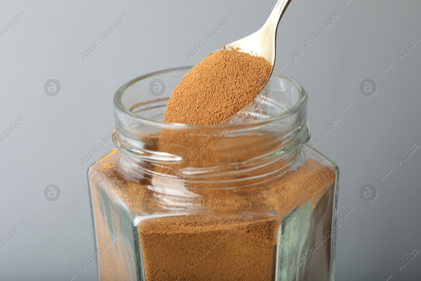 Taking instant coffee with spoon on grey background, closeup Photo of Taking instant coffee with spoon on grey background, closeup