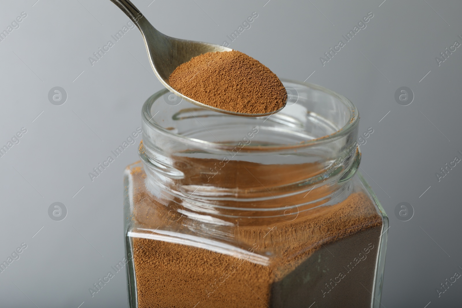Taking instant coffee with spoon on grey background, closeup Photo of Taking instant coffee with spoon on grey background, closeup