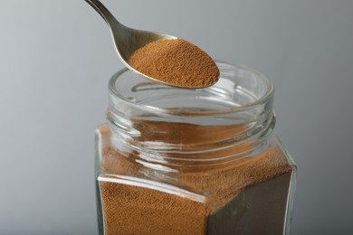 Photo of Taking instant coffee with spoon on grey background, closeup