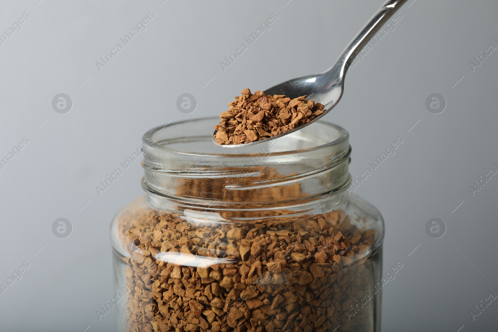 Taking instant coffee with spoon on grey background, closeup Photo of Taking instant coffee with spoon on grey background, closeup