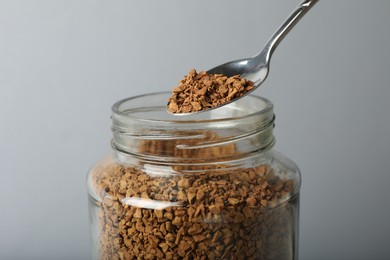 Photo of Taking instant coffee with spoon on grey background, closeup