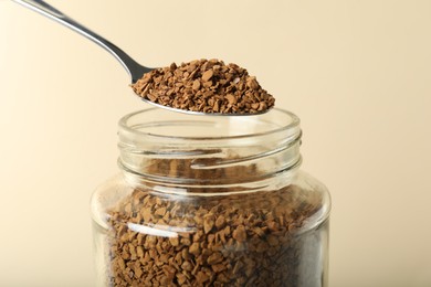 Photo of Taking instant coffee with spoon on beige background, closeup