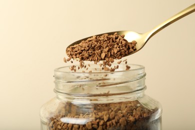 Photo of Taking instant coffee with spoon on beige background, closeup