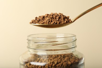 Photo of Taking instant coffee with spoon on beige background, closeup