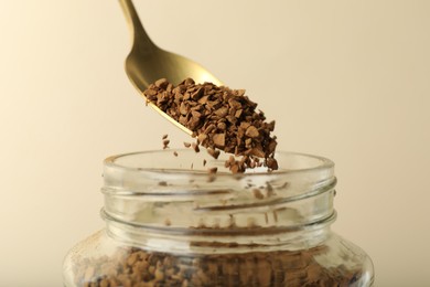 Photo of Taking instant coffee with spoon on beige background, closeup