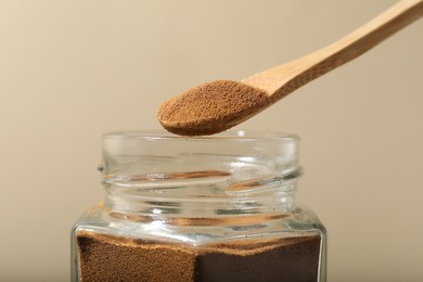 Photo of Taking instant coffee with spoon on beige background, closeup