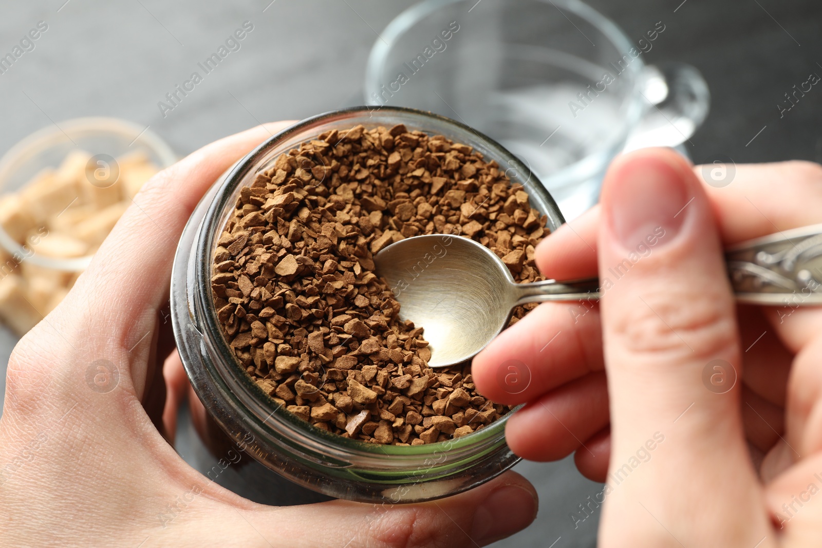 Woman taking instant coffee from jar at table, closeup Photo of Woman taking instant coffee from jar at table, closeup