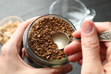 Photo of Woman taking instant coffee from jar at table, closeup