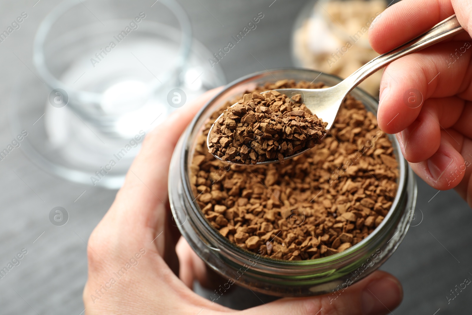 Woman taking instant coffee from jar at table, closeup Photo of Woman taking instant coffee from jar at table, closeup