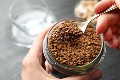 Photo of Woman taking instant coffee from jar at table, closeup