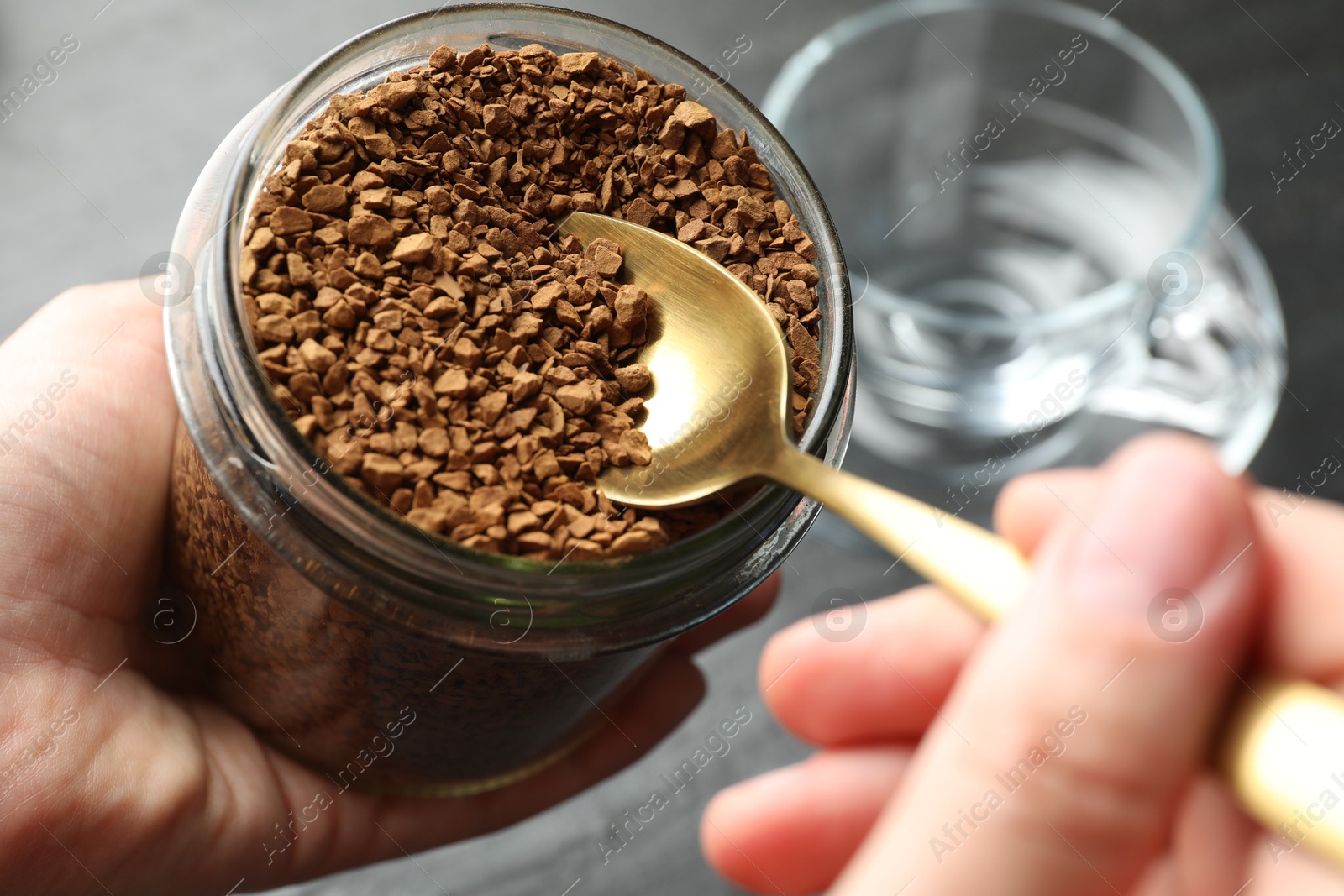 Woman taking instant coffee from jar at table, closeup Photo of Woman taking instant coffee from jar at table, closeup