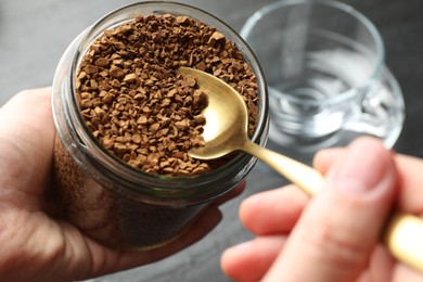 Photo of Woman taking instant coffee from jar at table, closeup