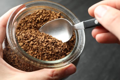 Photo of Woman taking instant coffee from jar at table, closeup