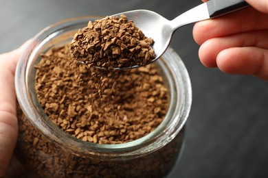 Photo of Woman taking instant coffee from jar at table, closeup