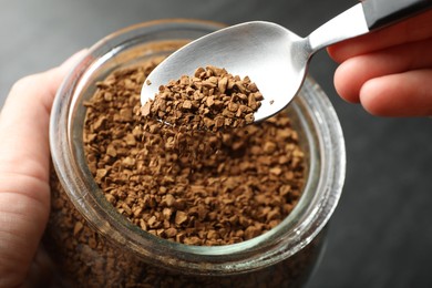 Photo of Woman taking instant coffee from jar at table, closeup