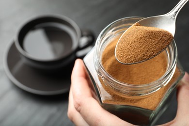 Photo of Woman taking instant coffee from jar at table, closeup