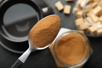 Photo of Spoon with instant coffee on blurred background, top view