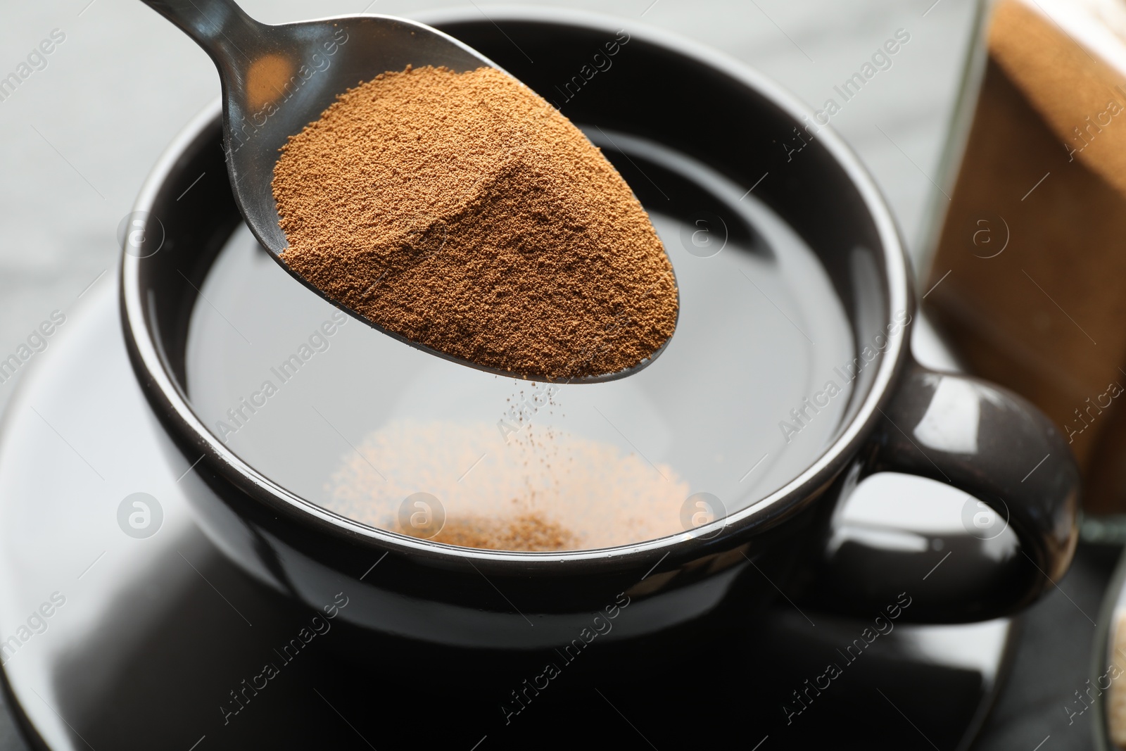 Putting instant coffee into cup at table, closeup Photo of Putting instant coffee into cup at table, closeup
