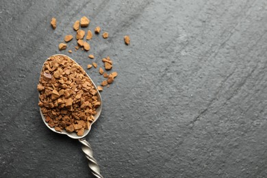 Photo of Spoon with instant coffee on black table, top view. Space for text