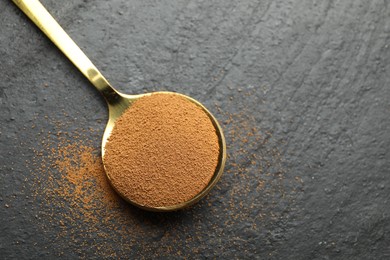 Photo of Spoon with instant coffee on black table, top view. Space for text