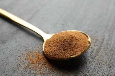 Photo of Spoon with instant coffee on black table, closeup
