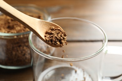 Photo of Putting instant coffee into cup at table, closeup