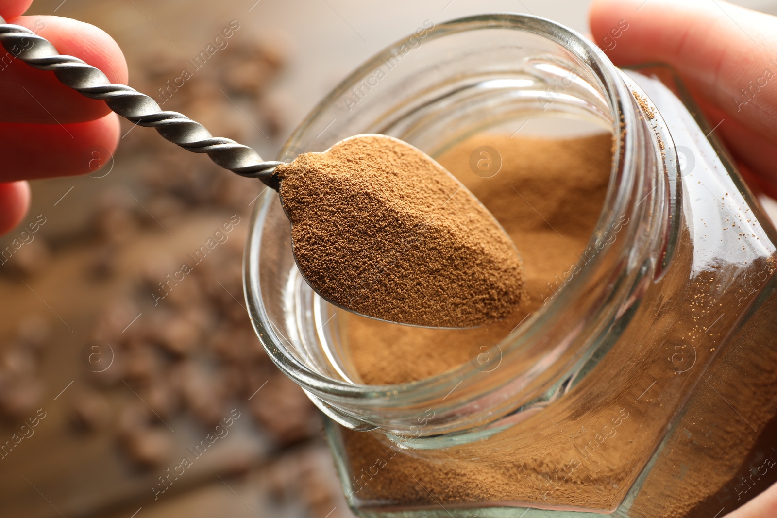 Woman taking instant coffee from jar on blurred background, closeup Photo of Woman taking instant coffee from jar on blurred background, closeup