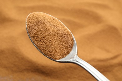 Photo of Spoon with aromatic instant coffee as background, closeup