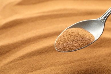 Photo of Spoon with aromatic instant coffee as background, closeup