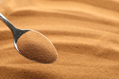 Photo of Spoon with aromatic instant coffee as background, closeup