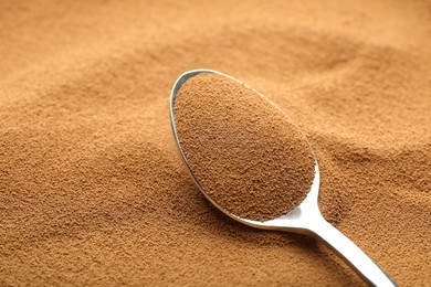 Photo of Spoon with aromatic instant coffee as background, closeup